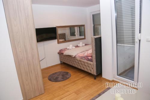 een kleine slaapkamer met een bed en een spiegel bij Apartman Tovilovic in Doboj