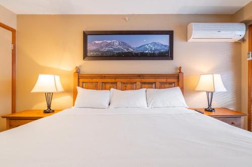 a bedroom with a large white bed with two lamps at #433 The Aspens On Blackcomb in Whistler