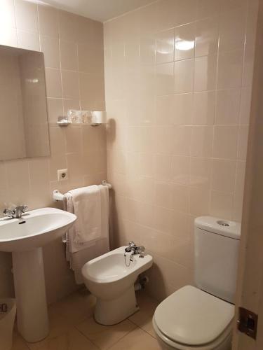 uma casa de banho com um WC branco e um lavatório. em Hostal Galicia em Figueres