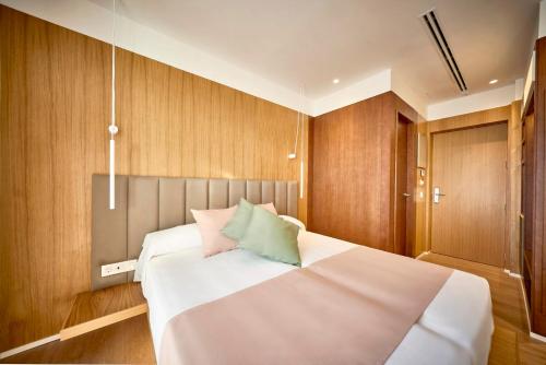 a bedroom with a large white bed with wooden walls at Hostal Pericón in Conil de la Frontera