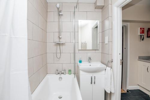 ein weißes Badezimmer mit einer Badewanne und einem Waschbecken in der Unterkunft Honeysuckle terrace in Henley on Thames