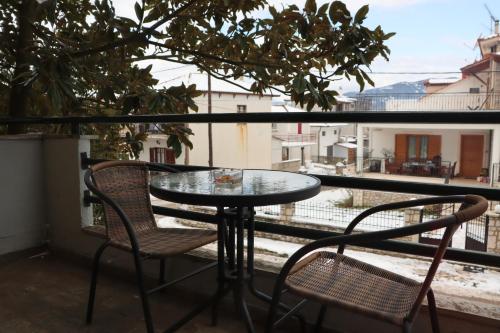 a table and chairs on a balcony with a view at Tzovolos Apartments in Kalavrita