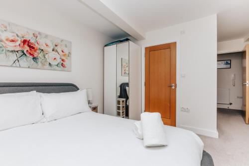 a bedroom with a white bed and a wooden door at Central Modern Flat for 4-6 & dedicated parking in Henley on Thames