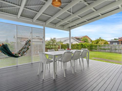 a white dining table and chairs on a deck at Rosena - The Classic Beach House - 5 Cashmore Street in Evans Head