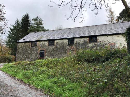 an old stone building on the side of a dirt road at The Old Milking Parlour in Llandovery