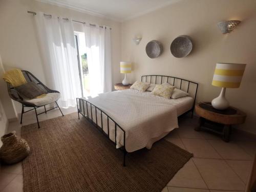 een slaapkamer met een bed, een stoel en een raam bij Alvor Vila da Praia in Alvor