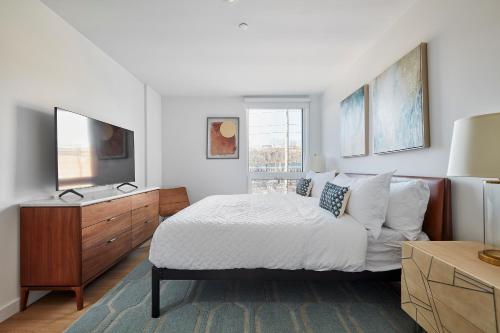 a bedroom with a bed and a dresser and a television at Harmony Lofts on Jackson 2 in Hoboken
