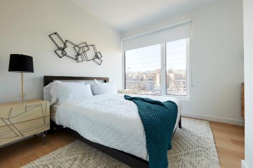 a white bedroom with a bed and a window at Harmony Lofts on Jackson 2 in Hoboken