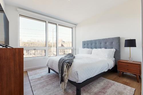 a white bedroom with a large bed and windows at Harmony Lofts on Jackson 2 in Hoboken