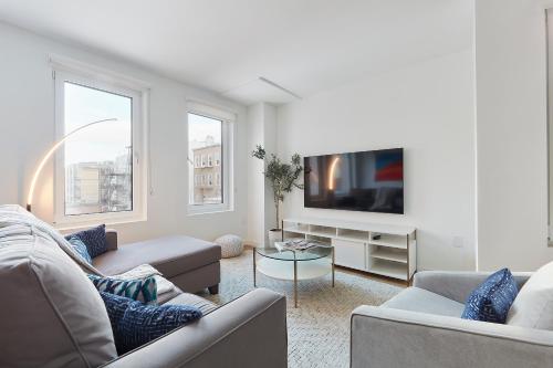 a living room with two couches and a flat screen tv at Harmony Lofts on Jackson 2 in Hoboken