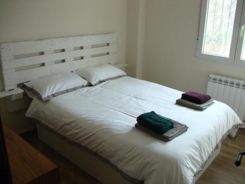 a white bed with two towels on top of it at Chalet con piscina y BBQ para 10 personas in San Martín de Valdeiglesias