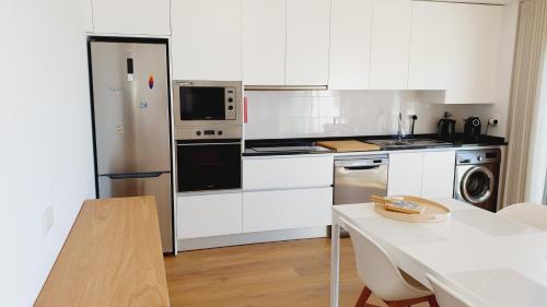 a kitchen with white cabinets and a white table at Veronique Apartment in Nazaré