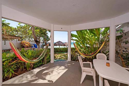 a porch with two hammocks and a table and chairs at Beach House Condos, Negril in Negril
