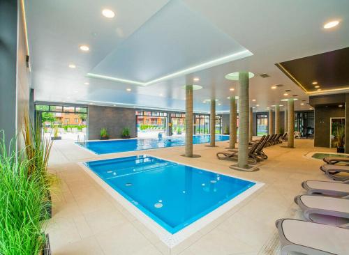duży basen w budynku z krzesłami w obiekcie Apartaments SWEET HOME AQUA & SPA w Kołobrzegu