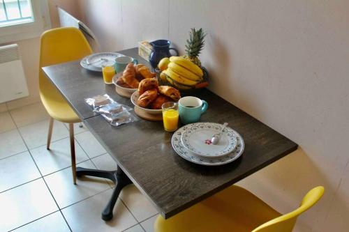 a table with a plate of food and bananas on it at Normandy Confort - WIFI & CALM - Bayeux Centre in Bayeux