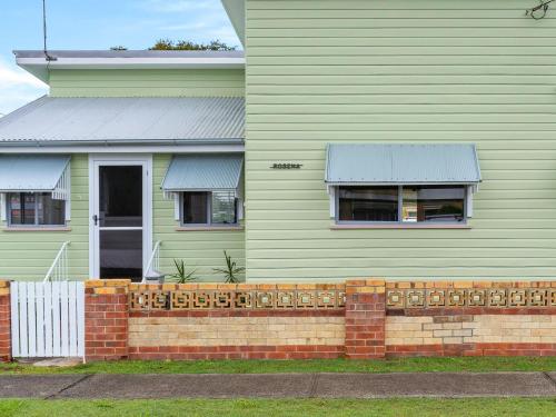 a green house with a brick fence in front of it at Rosena - The Classic Beach House - 5 Cashmore Street in Evans Head