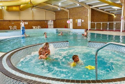 a group of people in a swimming pool at The Sea Breeze - 8 Berth Premium Caravan in Camber Sands in Camber