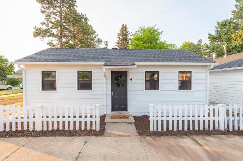a white house with a white fence in front of it at Spearfish Cottages in Spearfish