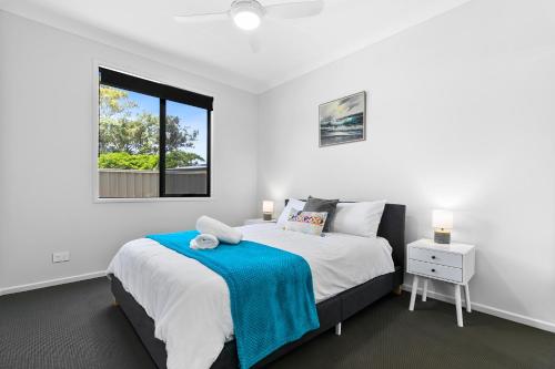a white bedroom with a bed and a window at Bribie Getaway Villa in Bongaree