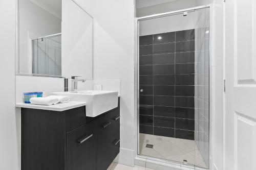 a bathroom with a shower and a sink and a mirror at Bribie Getaway Villa in Bongaree