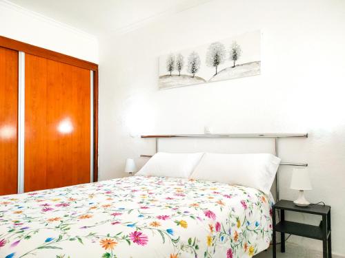 1 dormitorio con 1 cama con colcha de flores en Cozy Beach Holiday Home in Playa del Ingles, en Playa del Inglés