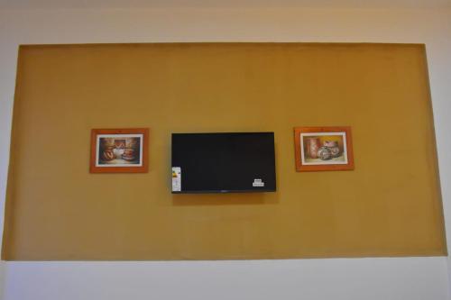 a flat screen tv on a wall with two pictures at Habitación con oficina a la calle in La Rioja
