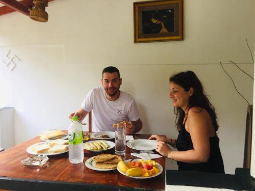 a man and a woman sitting at a table with food at orchid villa in Ella