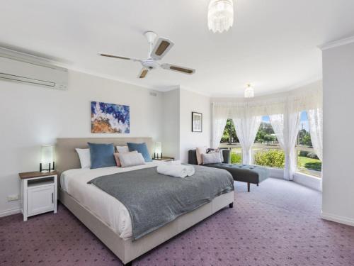 a white bedroom with a large bed and a window at Rose Retreat in Port Fairy
