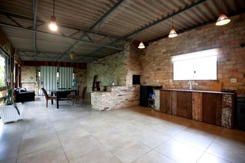 um quarto grande com uma mesa e uma parede de tijolos em Joaquina Guest House em Florianópolis