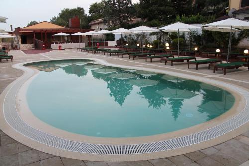 a large swimming pool with tables and umbrellas at Hotel Ristorante Belvedere in Caserta