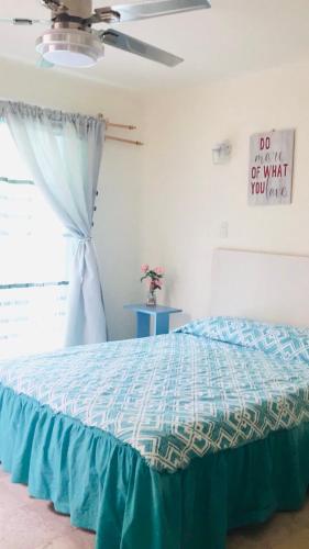 a bedroom with a bed with a blue comforter and a window at Casa Brisa sol in Acapulco
