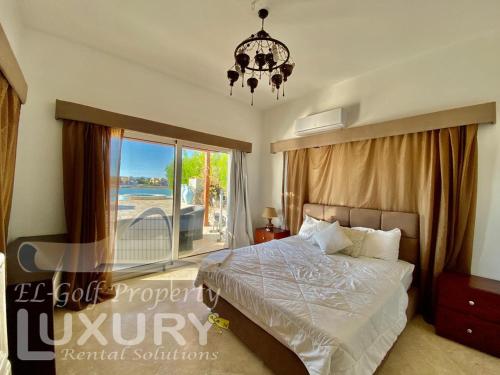 Schlafzimmer mit einem Bett, einem Fenster und einem Kronleuchter in der Unterkunft Villa 9 ph-5 with 4 Bed Room in Hurghada