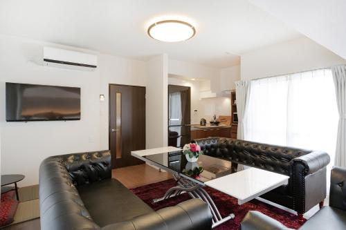 a living room with a leather couch and a table at Ideal Fukushima in Osaka
