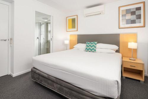 a bedroom with a large white bed and a lamp at Corrigans Cove in Batemans Bay