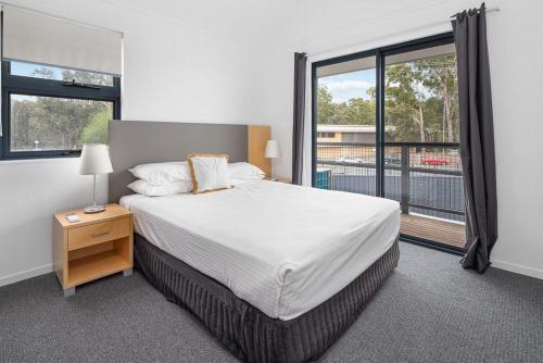 a bedroom with a bed and a large window at Corrigans Cove in Batemans Bay