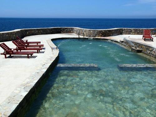 a swimming pool with chairs and the ocean in the background at Villa Lyudmila in Utjeha