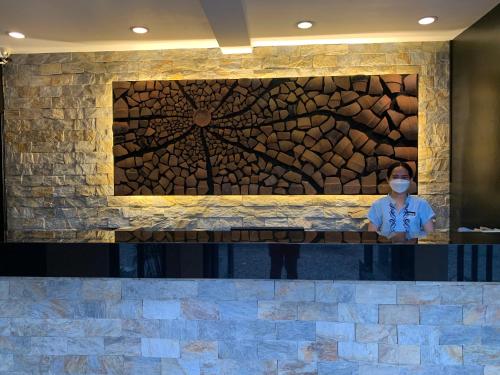 a person wearing a face mask in front of a stone wall at The Henry Resort Taramindu Laiya in Batangas City