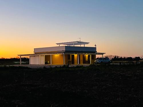 a house in a field with the sunset in the background at Agriturismo La Costa dei Trabocchi in Torino di Sangro