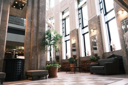 a lobby with tables and chairs and large windows at Kurashiki Royal Art Hotel in Kurashiki