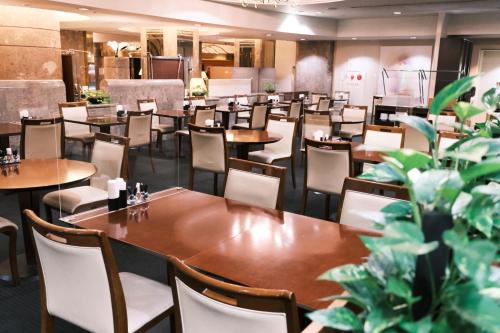 a dining room with tables and chairs and plants at Kurashiki Royal Art Hotel in Kurashiki
