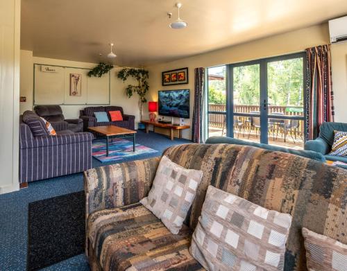 a living room with couches and a balcony at Kakapo Lodge in Hanmer Springs