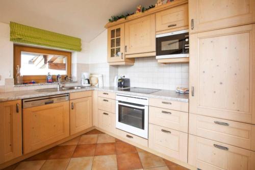 a kitchen with wooden cabinets and a sink and a microwave at Holiday flats B rlerhof K nigsleiten in Königsleiten