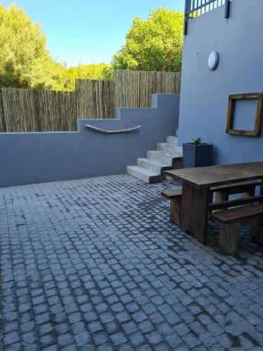 a patio with a wooden table and a fence at Still Bay East Beach Apartment in Stilbaai