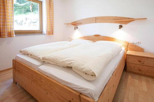 a wooden bed in a room with a window at Holiday flat B rlerhof XXL K nigsleiten in Königsleiten