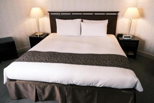 a large bed in a hotel room with two lamps at Kurashiki Royal Art Hotel in Kurashiki