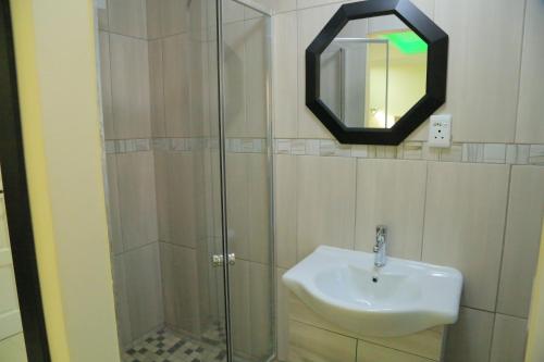a bathroom with a sink and a glass shower at Classy Guest House in Johannesburg