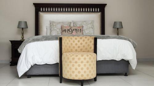 a bedroom with a large bed with a chair at Letsatsing Lodge in Rustenburg