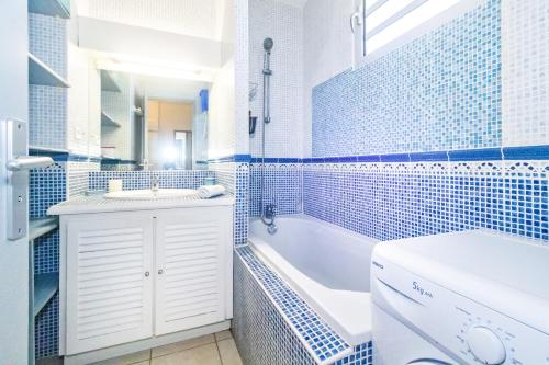 ein blau-weißes Bad mit einer Badewanne und einem Waschbecken in der Unterkunft Purple - Duplex cosy en plein cœur de l'Hermitage, proche du lagon in L'Ermitage-Les-Bains