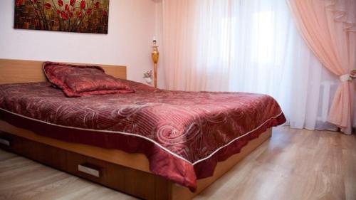 a bedroom with a bed with a red comforter at Apartments Tiraspol in Tiraspol