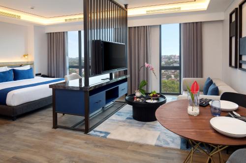 a hotel room with a king bed and a living room at Hotel Aruss Semarang in Semarang